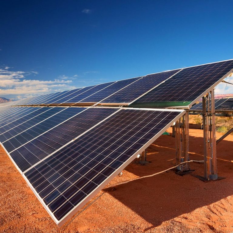 Solar panels installed in a desert landscape under a clear blue sky.